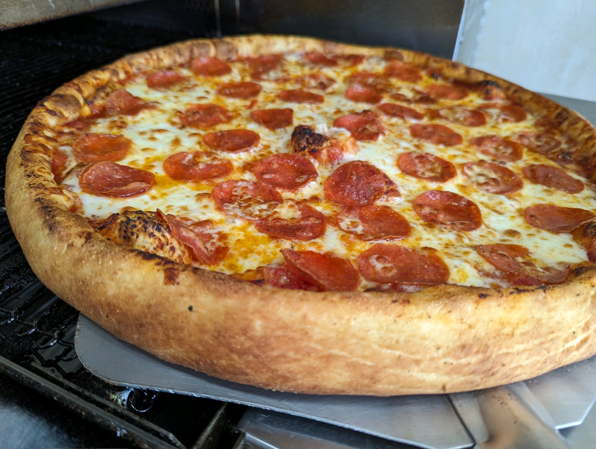 Image of a whole pepperoni pizza fresh out of the oven.